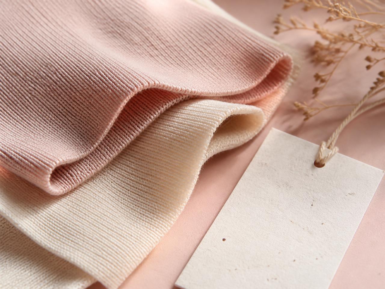 Blush and ivory recycled knit fabric swatches with a certification tag